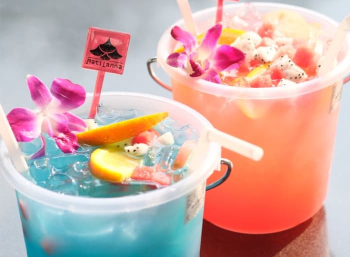 Colorful Thai bucket drinks filled with alcohol, ice, and straws, popular among tourists at Thailand's Full Moon Parties.